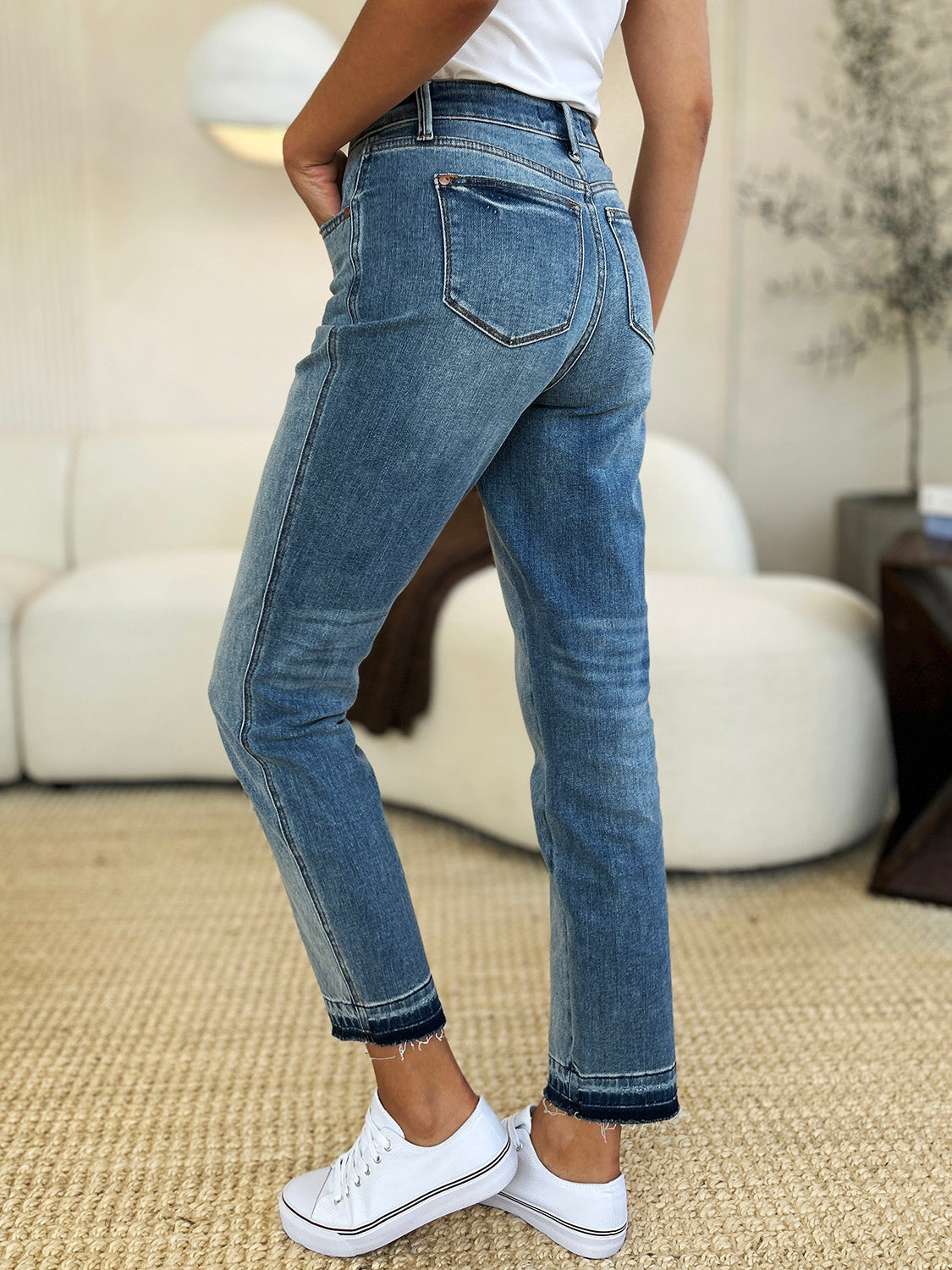 Judy Blue Full Size Mid Rise Rigid Magic Release Hem Jeans on model in white sneakers, side view.