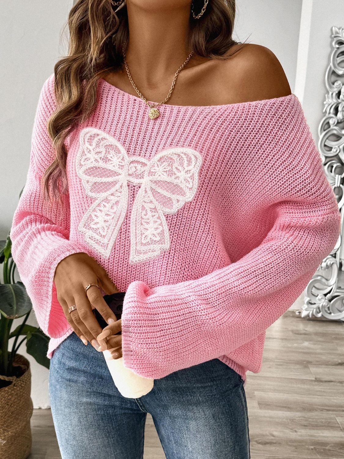 Pink long sleeve sweater with bow boat neck design and casual fit.