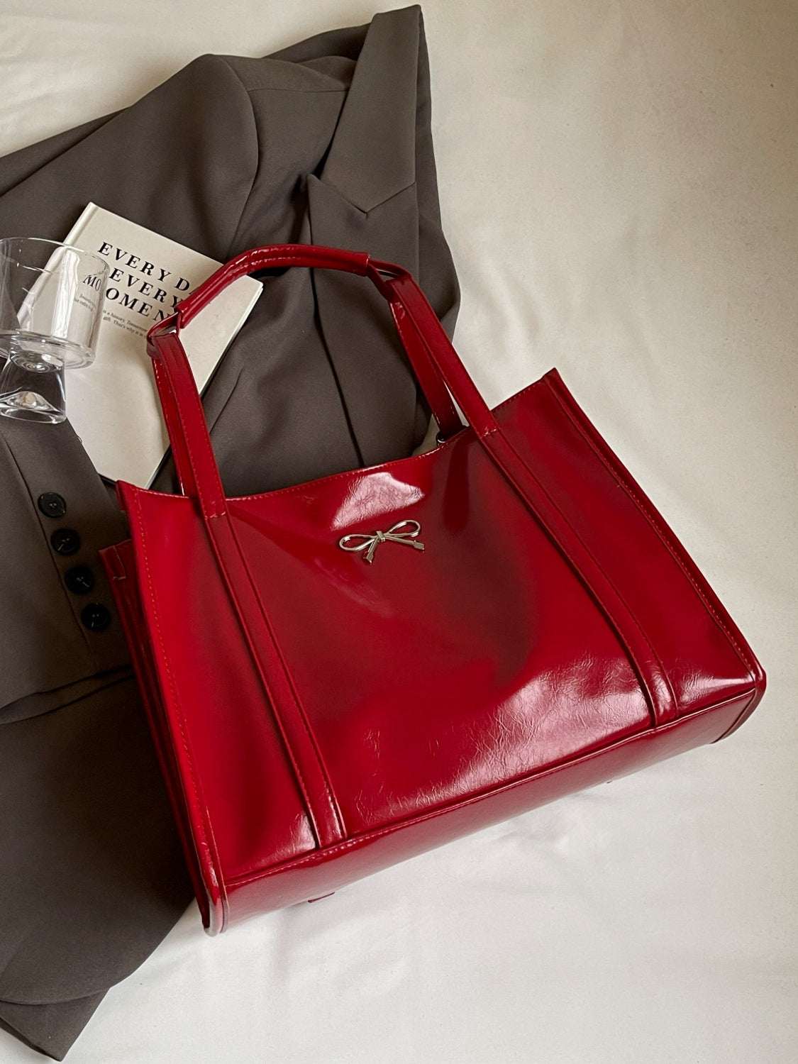 Red PU leather bow shoulder bag on a beige background.