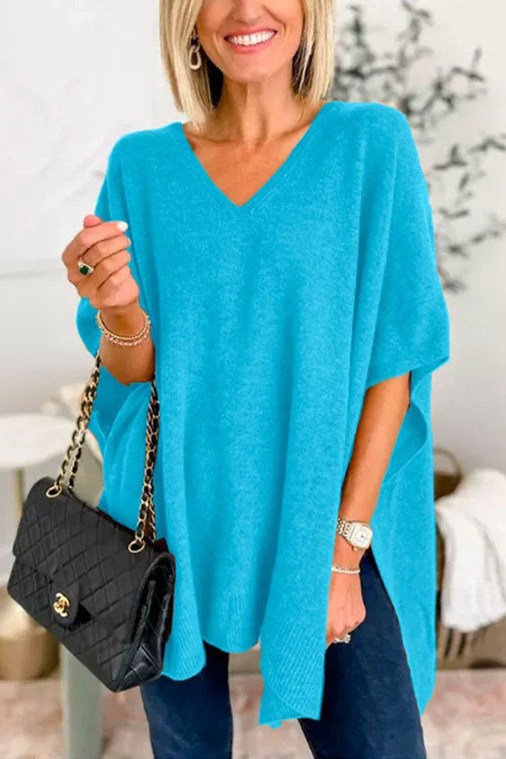 Blue slit V-neck half sleeve knit top on model holding a black handbag.