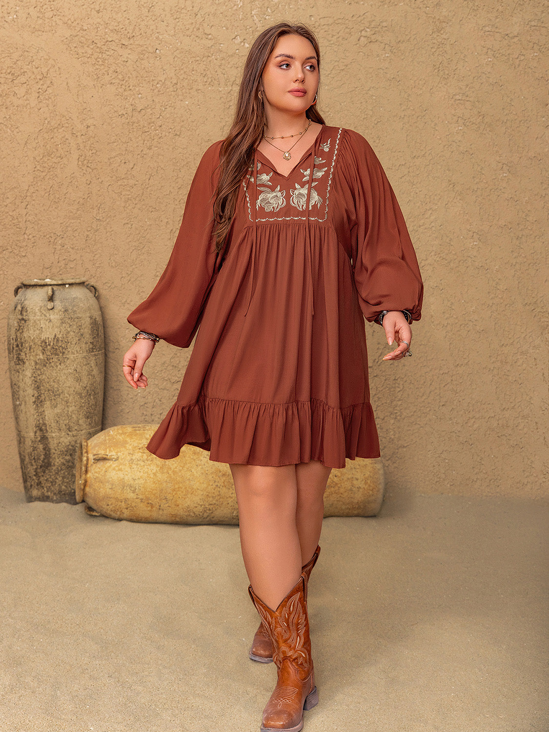 Plus size brown mini dress with embroidered tie neck and balloon sleeves.