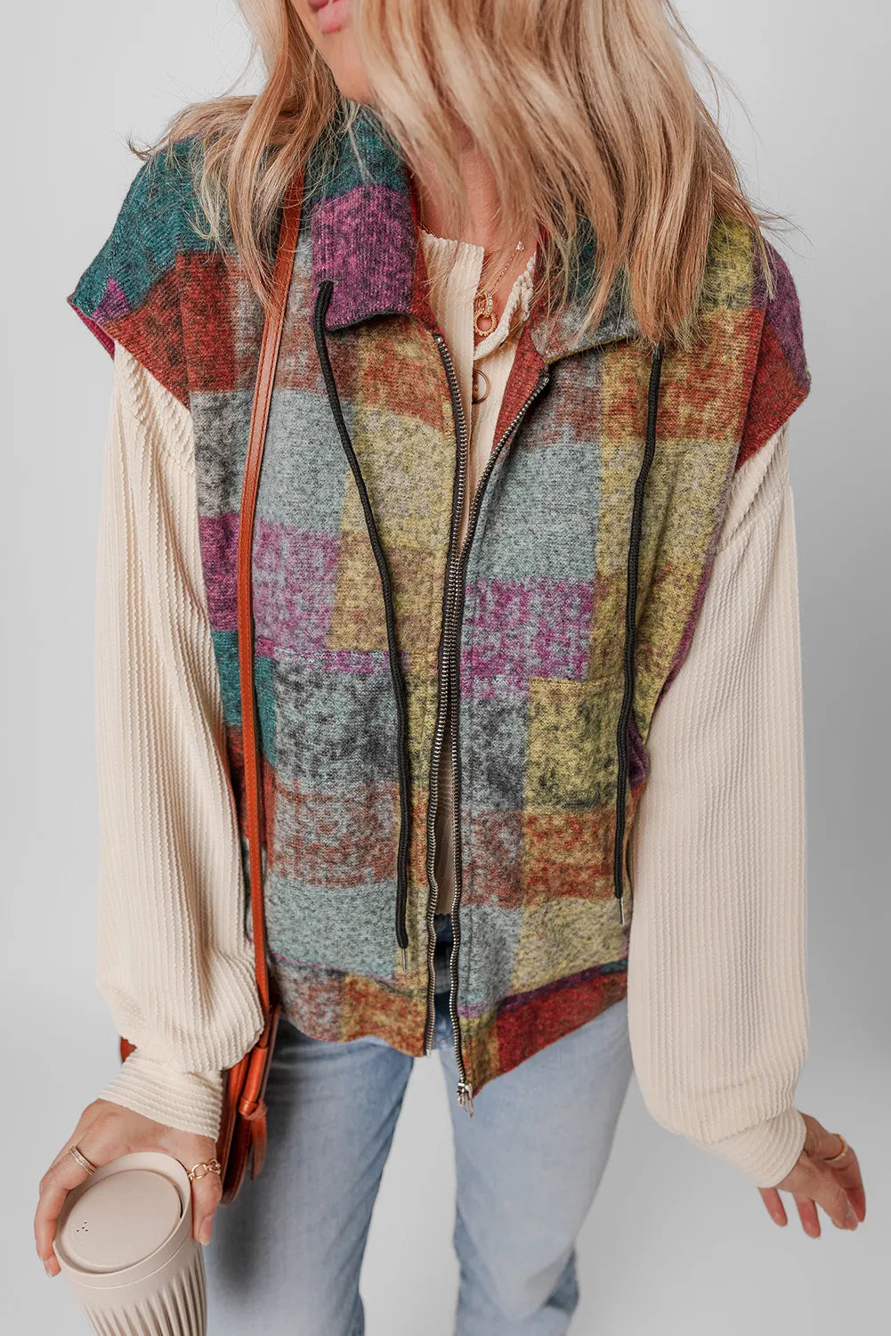 Plaid zip-up collared neck vest coat in colorful pattern, worn over a cream sweater, with a casual chic style.