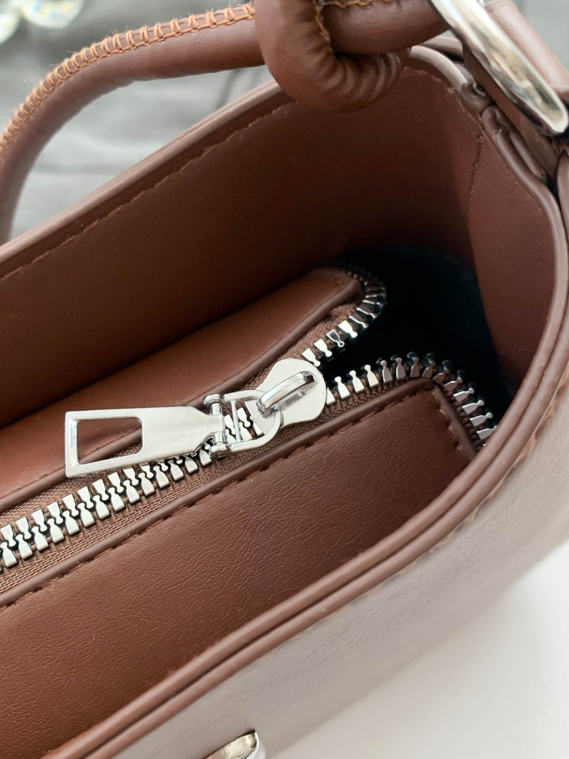 Small brown PU leather handbag with knotted strap and silver zipper.