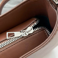 Small brown PU leather handbag with knotted strap and silver zipper.