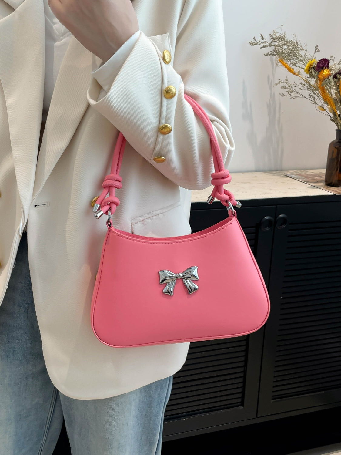 Small pink PU leather handbag with bow and knotted strap.