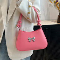 Small pink PU leather handbag with bow and knotted strap.