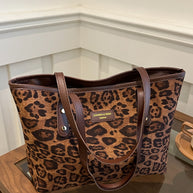 Leopard polyester tote bag on a table, large size with durable handles.