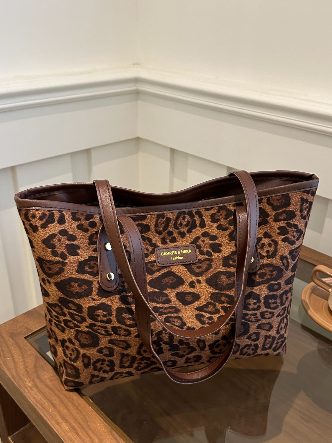 Leopard polyester tote bag on a table, large size with durable handles.