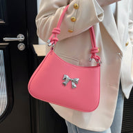 Small pink PU leather handbag with a knotted strap and decorative bow design.