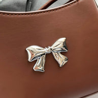 Small PU leather handbag with knotted strap and bow detail.