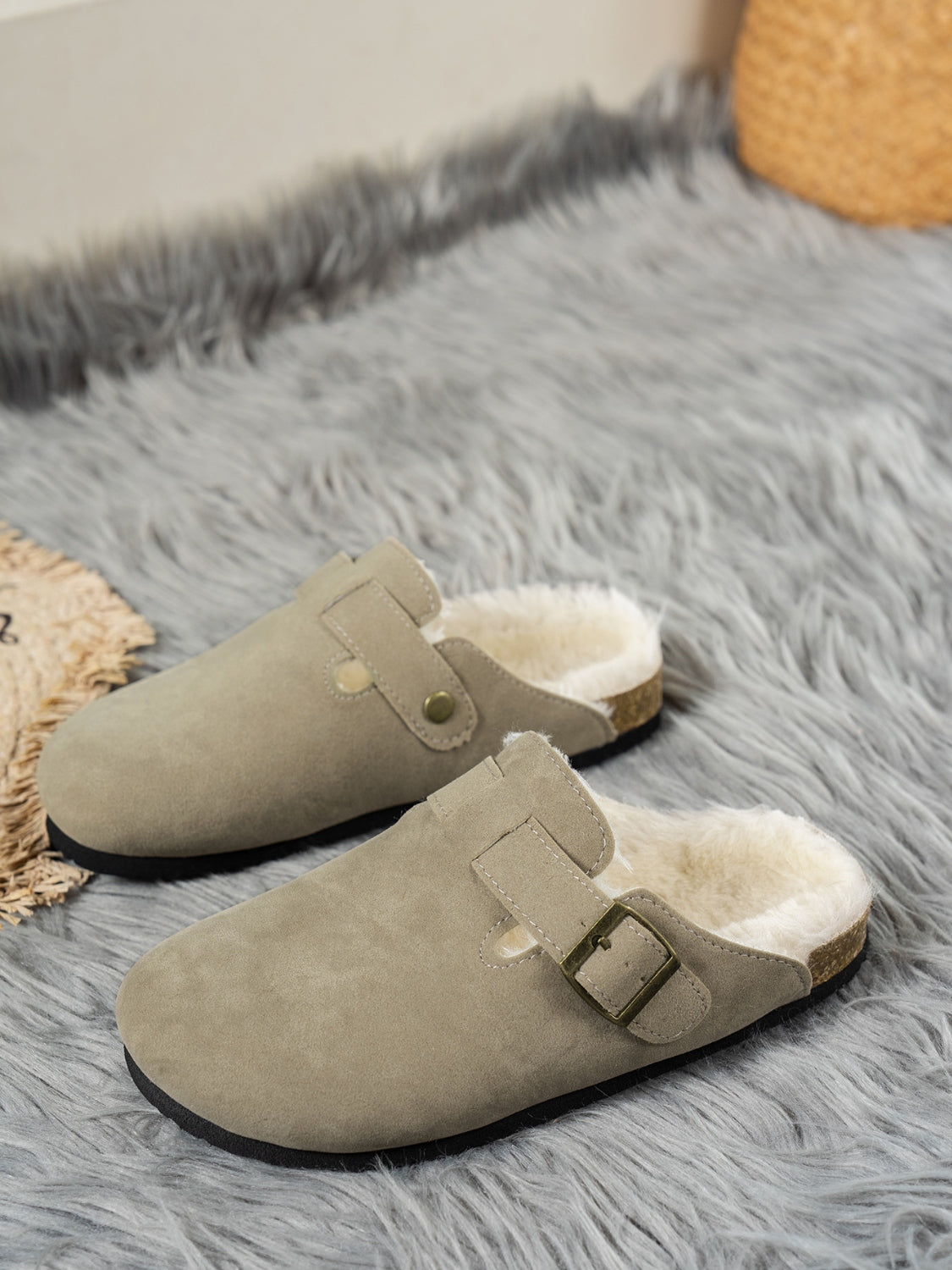 Suede round toe slippers with faux fur lining on a fluffy rug.