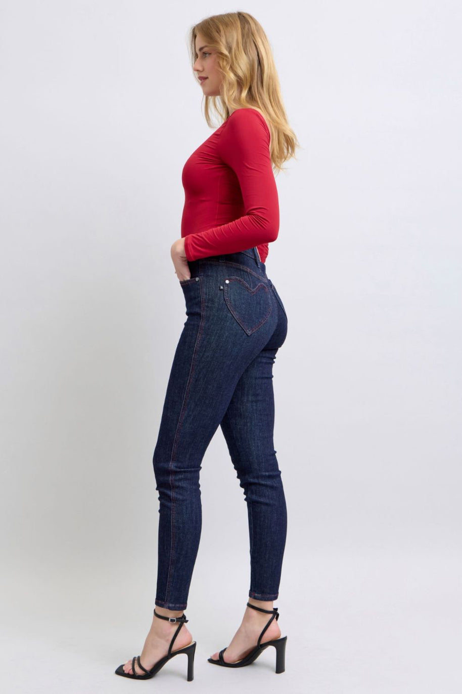 Judy Blue skinny jeans with heart-shaped back pockets, worn with a red top.