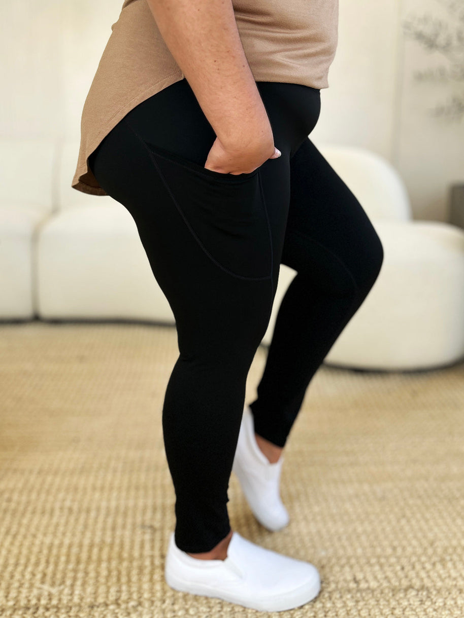 Wide waistband sports leggings in black, stretchy nylon-spandex material, shown on person standing sideways.