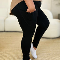 Wide waistband sports leggings in black, stretchy nylon-spandex material, shown on person standing sideways.