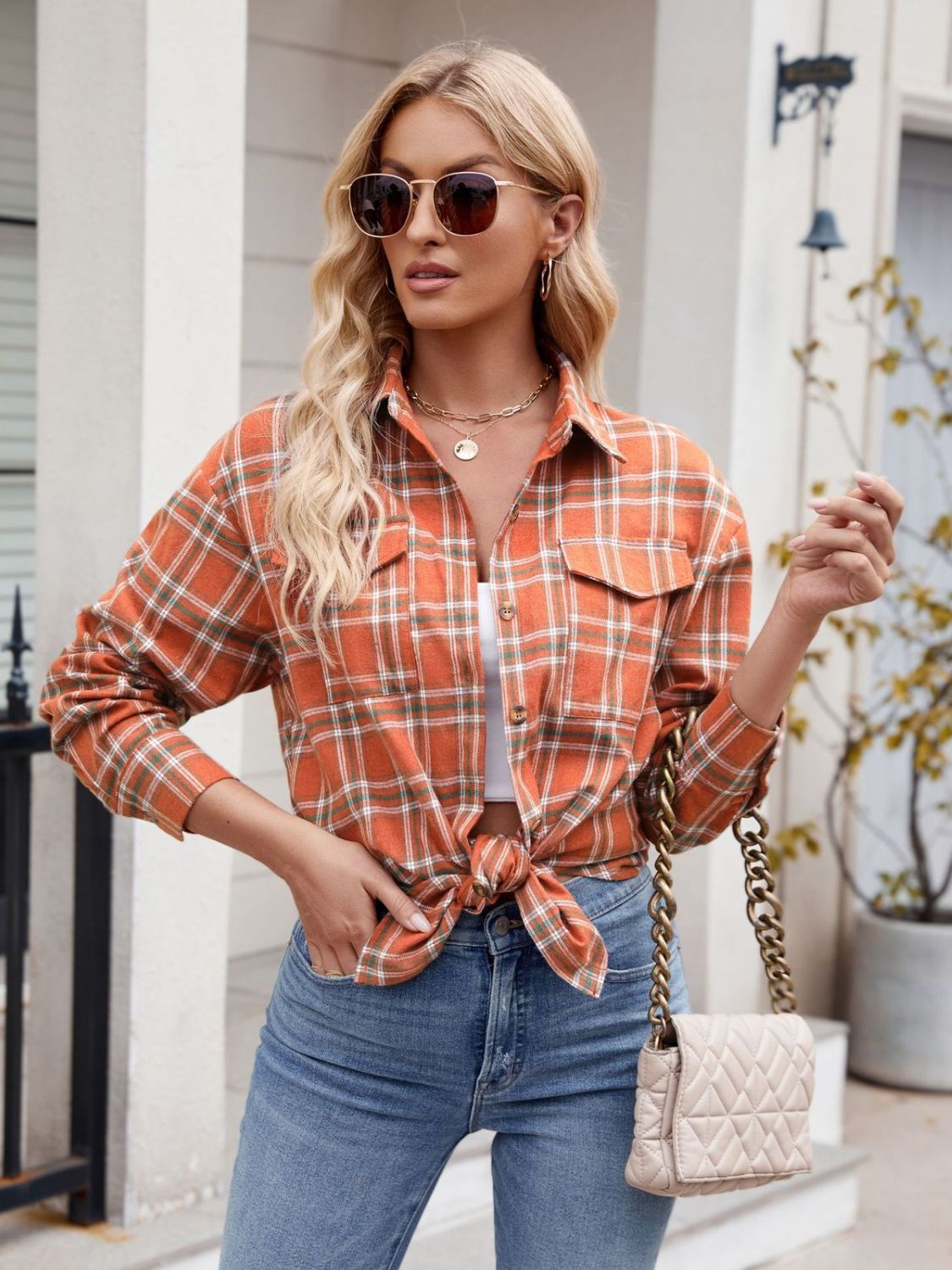 Woman wearing Mandy Plaid Button Up Long Sleeve Shirt with sunglasses and jeans, holding a quilted purse.