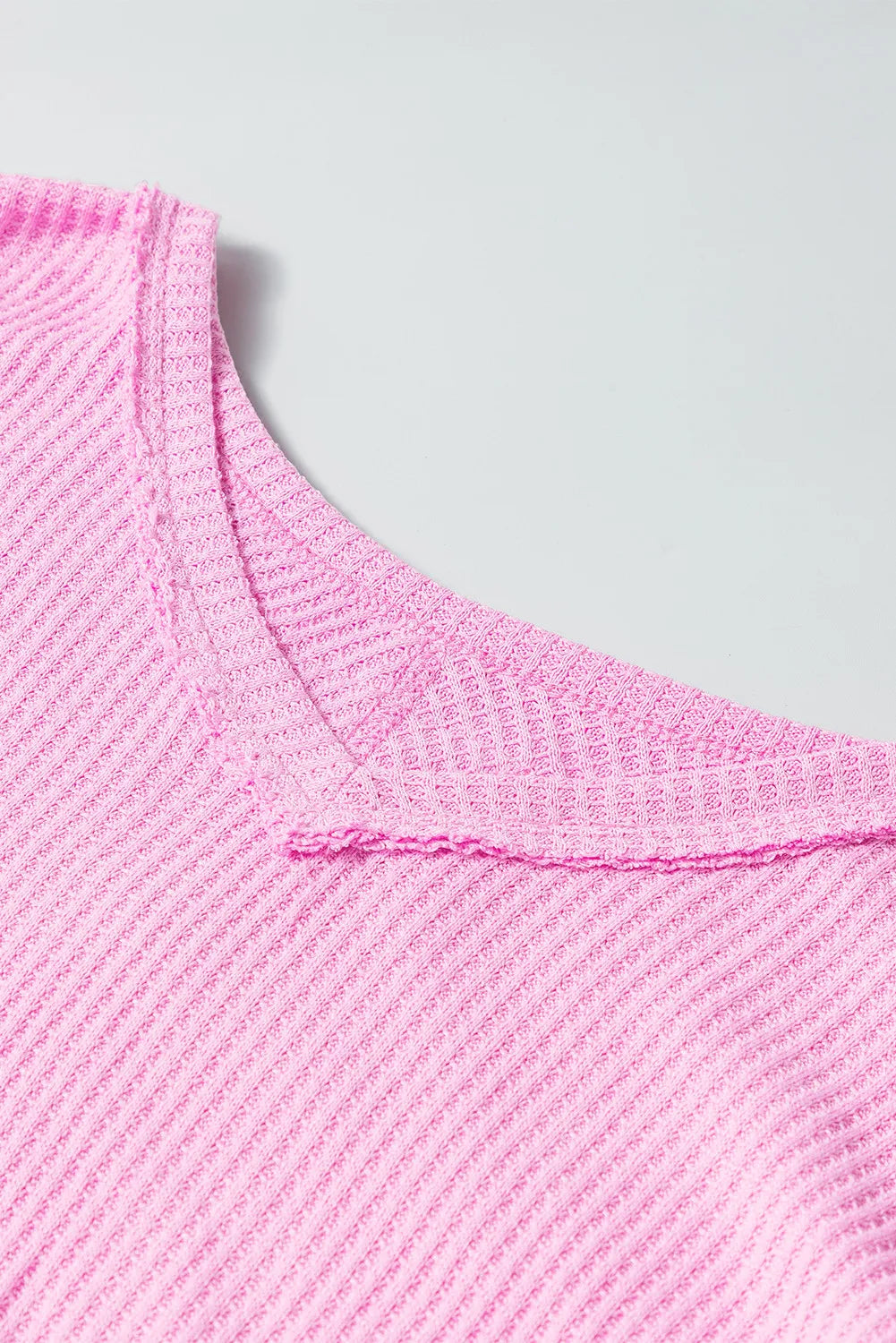 Pink waffle-knit V-neck long sleeve blouse.