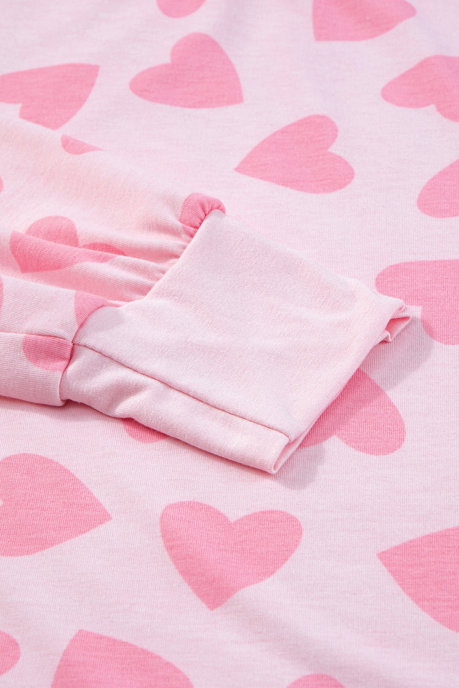 Pink heart print on long sleeve top fabric close-up.