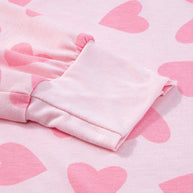 Pink heart print on long sleeve top fabric close-up.