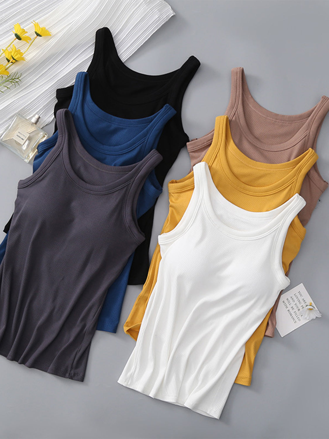 Various colors of round neck tank tops with integrated bras displayed on a surface.