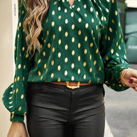 Cutout printed mock neck long sleeve blouse in dark green with gold accents, worn with black pants.