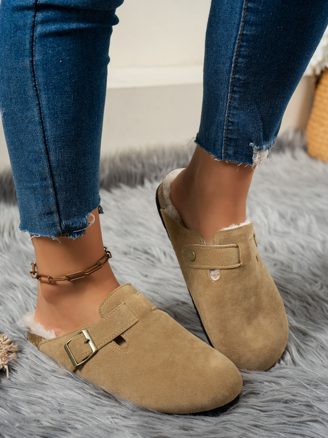 Suede round toe slippers with faux fur lining and flat heel, worn with jeans.