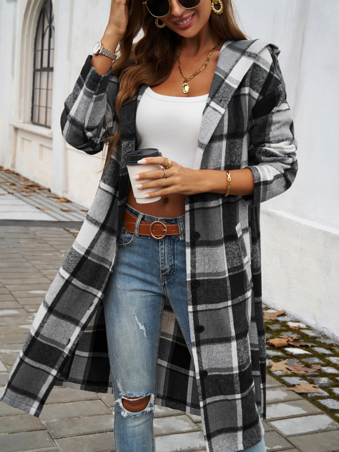 Plaid long sleeve hooded coat with button closure and pockets, worn by woman with jeans and a white top.