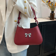 Small red bow PU leather handbag with knotted strap design.