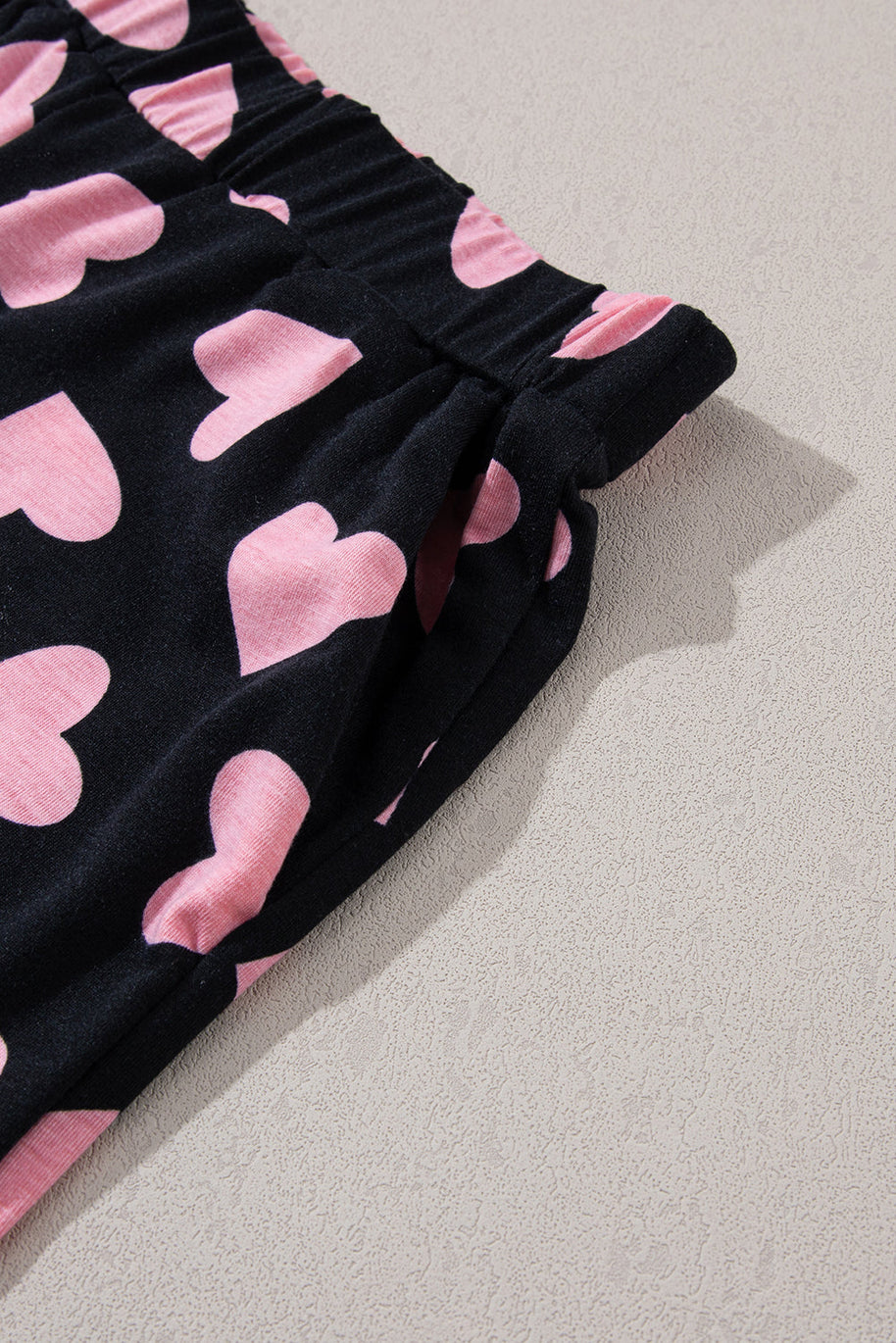 Heart print long sleeve top and shorts lounge set fabric with pink hearts on black background.