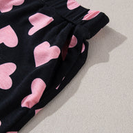 Heart print long sleeve top and shorts lounge set fabric with pink hearts on black background.