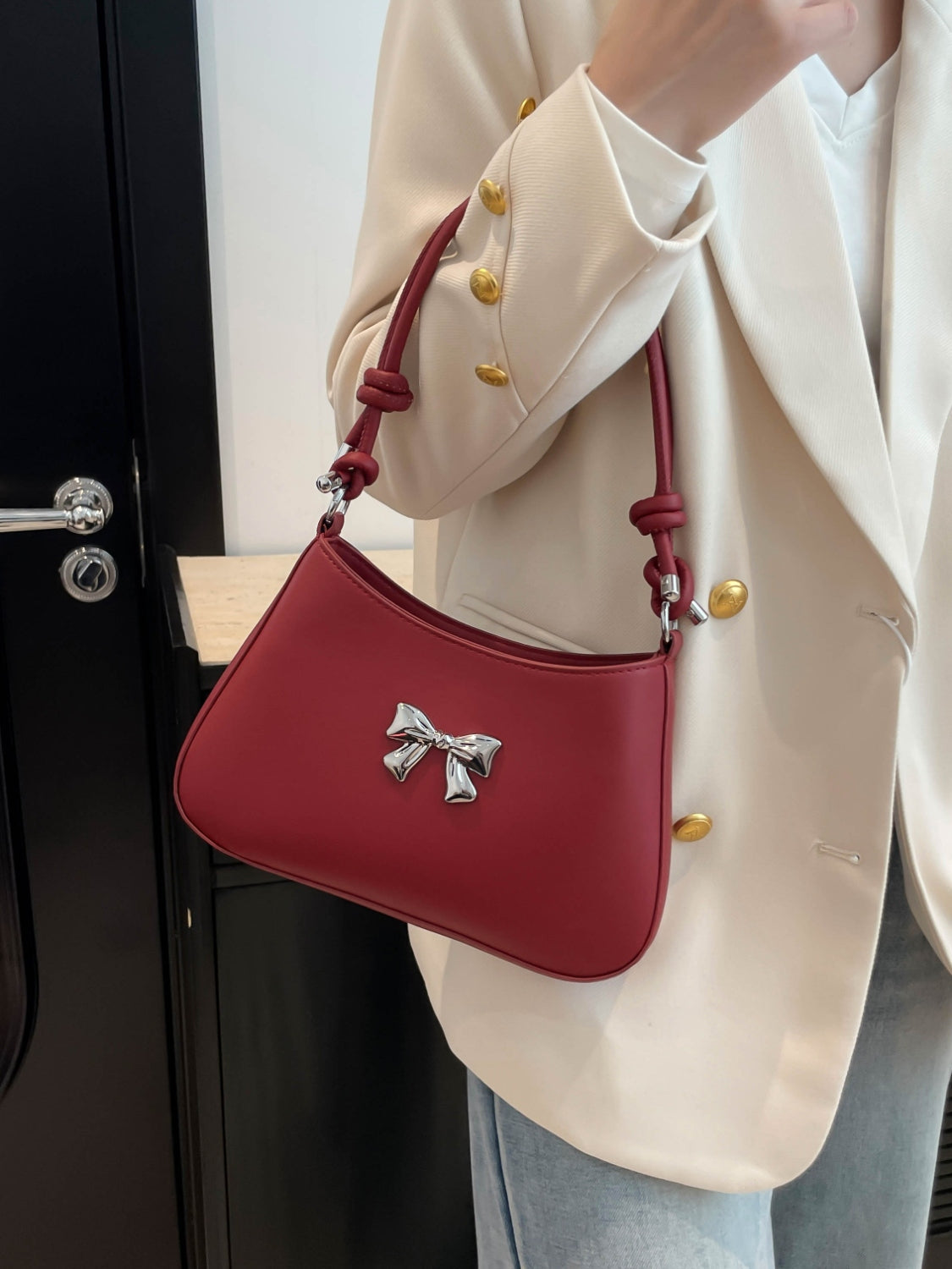 Small red PU leather handbag with knotted strap and bow detail.