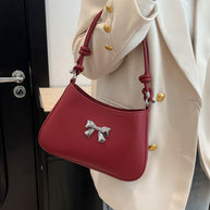 Small red PU leather handbag with knotted strap and bow detail.