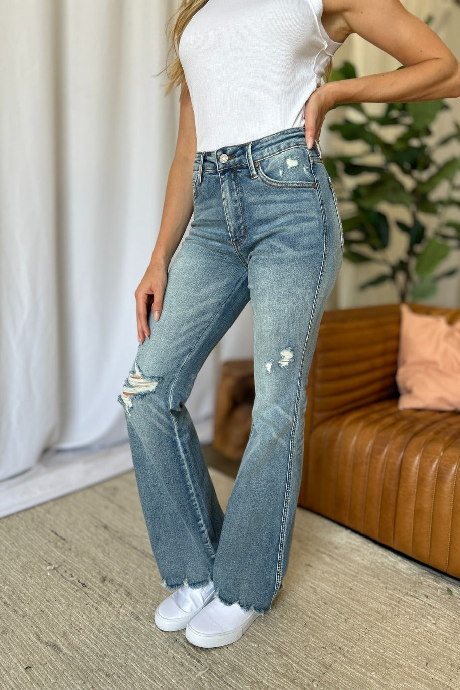 Judy Blue medium rise tummy control flare jeans with distressed detailing and raw hem.