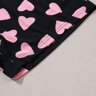 Heart print long sleeve top fabric detail with pink hearts on black background.