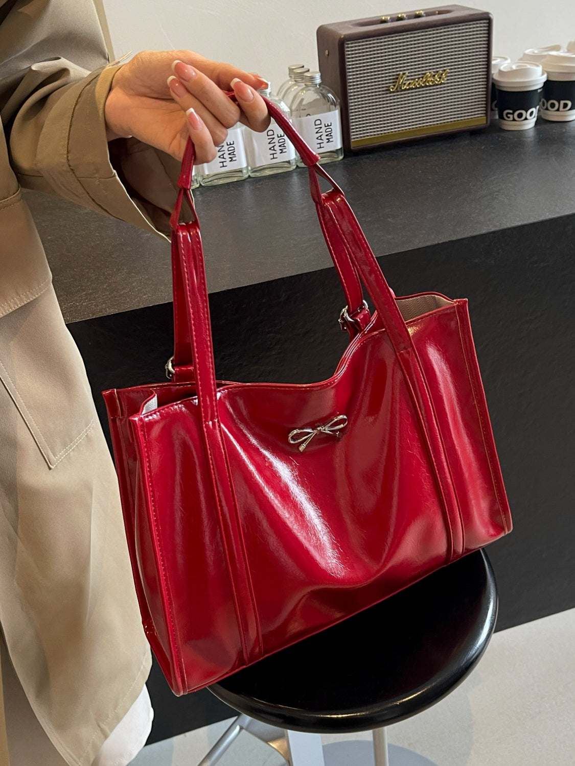 Red PU leather bow shoulder bag with spacious design on chair.