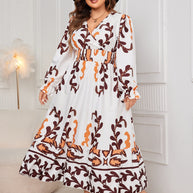 Plus size printed surplice flounce sleeve dress in white with orange and brown pattern.