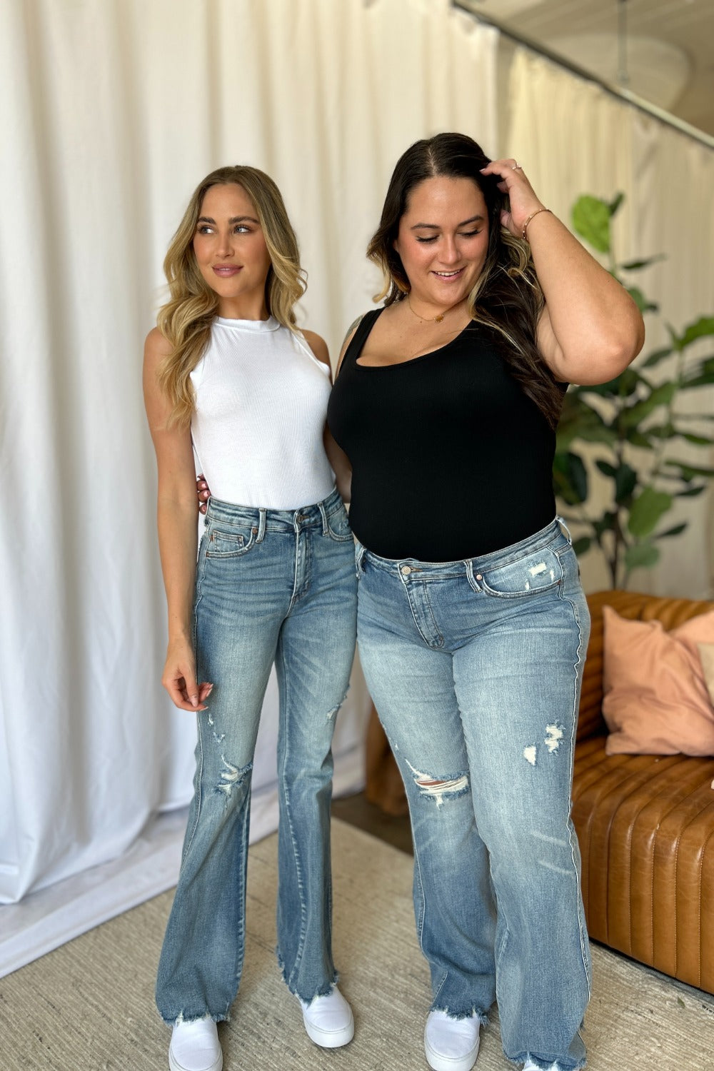 Judy Blue medium rise tummy control flare jeans with distressed detailing, worn by two models in a casual setting.