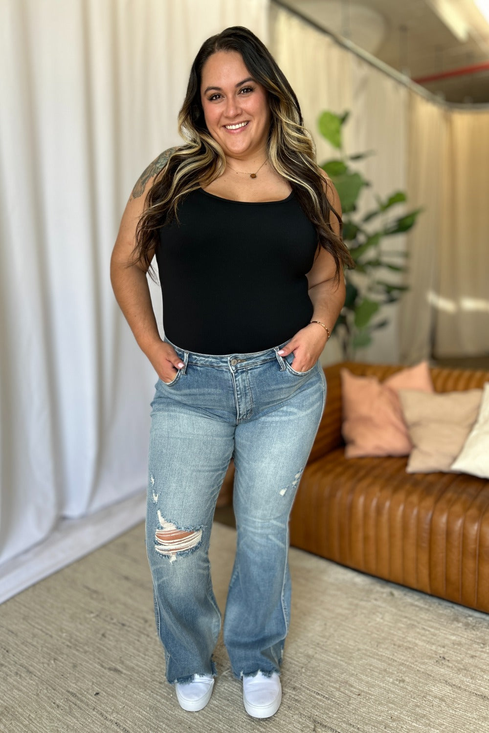 Judy Blue medium rise tummy control destroy flare jeans with distressed detailing, worn by a smiling woman in a casual setting.