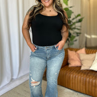 Judy Blue medium rise tummy control destroy flare jeans with distressed detailing, worn by a smiling woman in a casual setting.