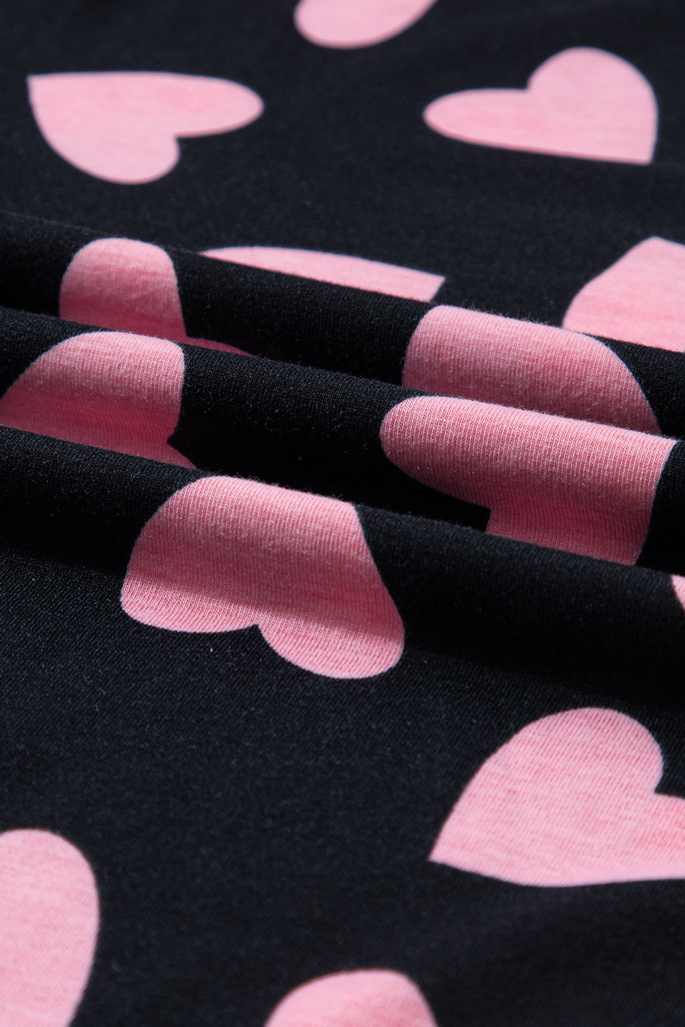 Close-up of pink heart print on a black fabric from a long sleeve top.