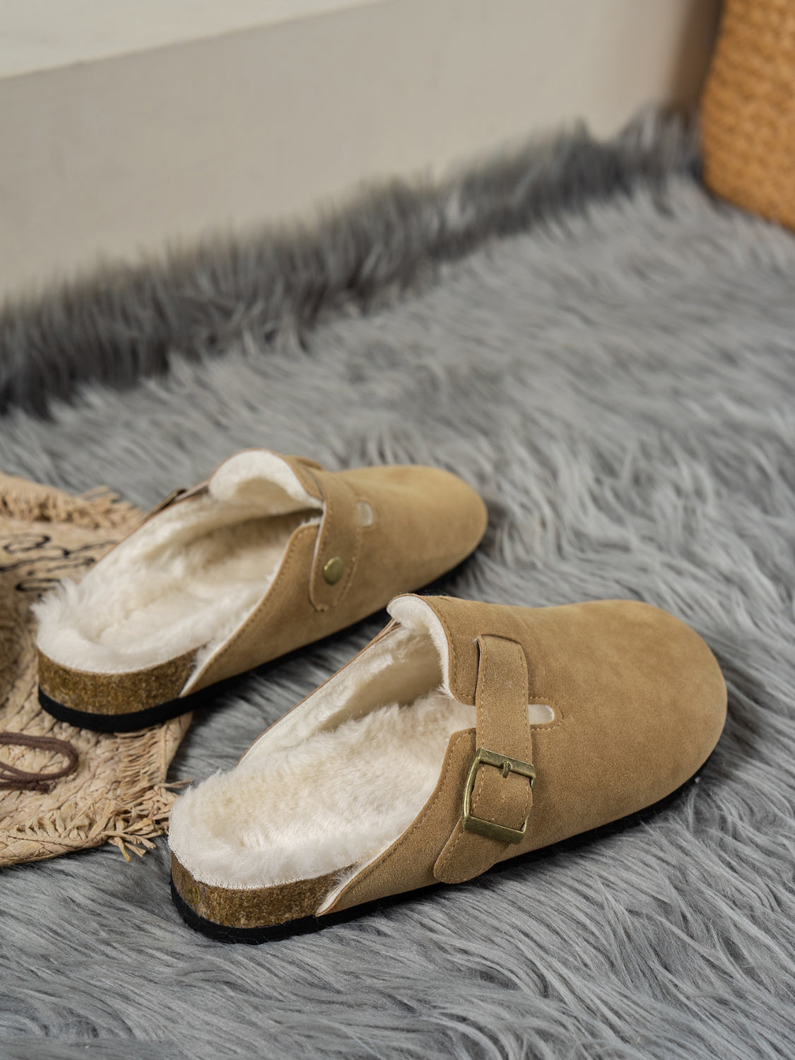 Suede round toe slippers with faux fur lining on a gray rug.