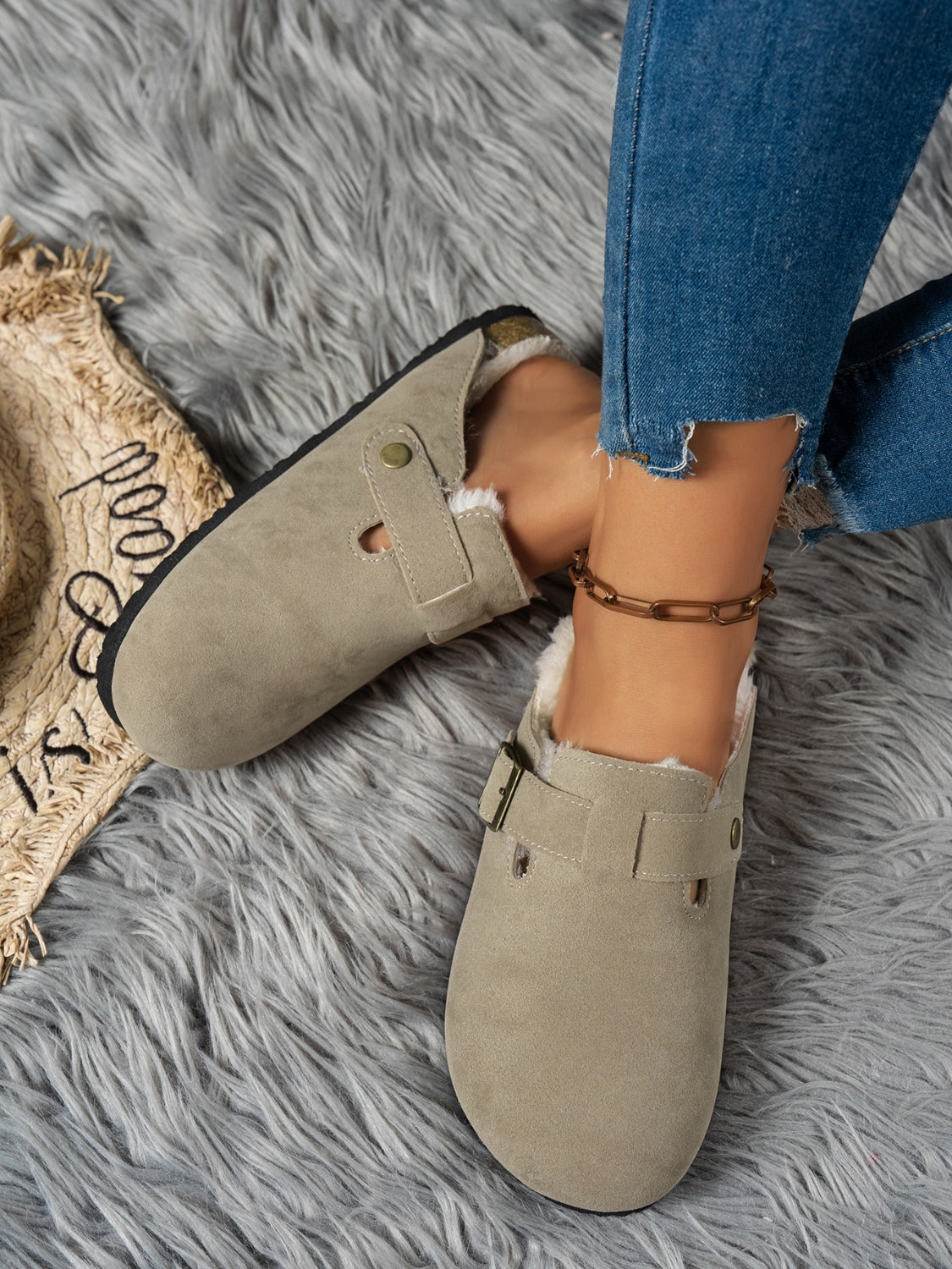 Suede round toe slippers with faux fur lining on a grey fur rug.