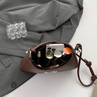 Small bow PU leather knotted strap handbag placed on a gray coat.