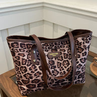 Leopard polyester tote bag with large size and brown handles on a table.