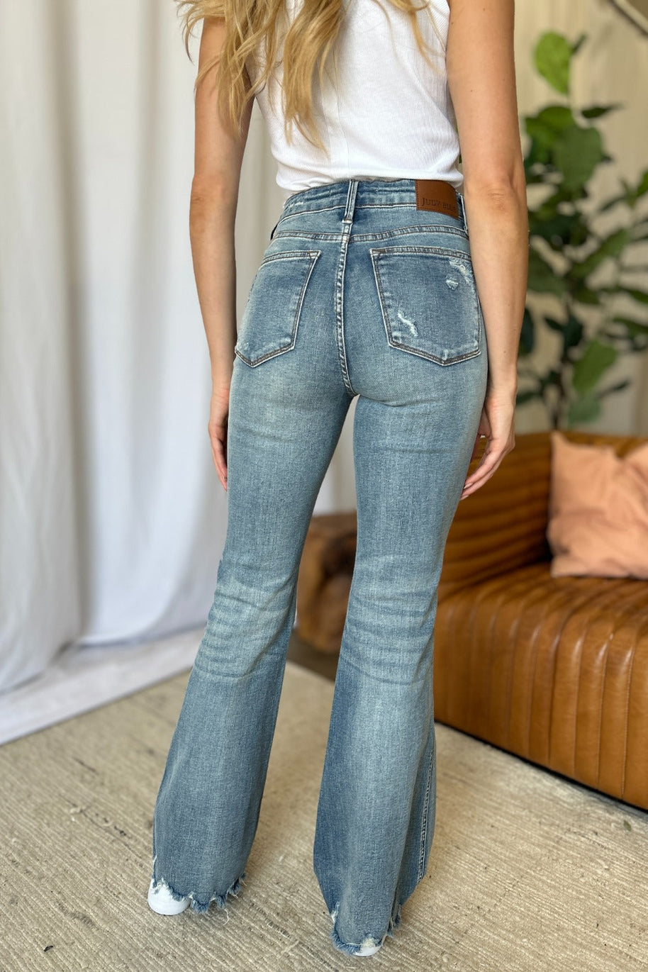 Judy Blue full size medium rise tummy control destroy flare jeans with distress detailing and raw hem, enhancing silhouette.