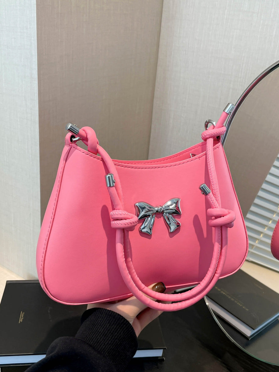 Small pink PU leather handbag with knotted strap and bow detail.