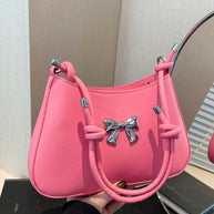 Small pink PU leather handbag with knotted strap and bow detail.