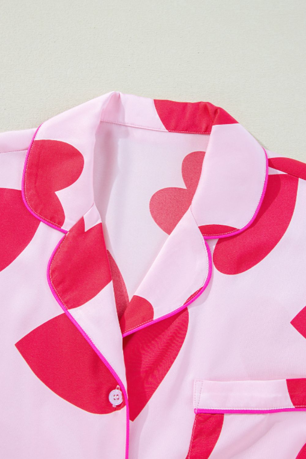 Heart collared neck short sleeve top with red heart pattern and pink piping.