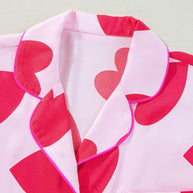 Heart collared neck short sleeve top with red heart pattern and pink piping.