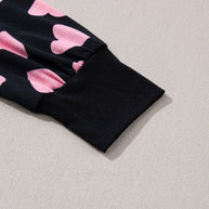 Heart print long sleeve top with pink hearts and black cuff detail.