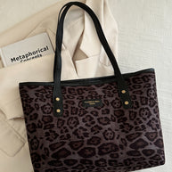 Leopard polyester tote bag on a white surface with black handles.